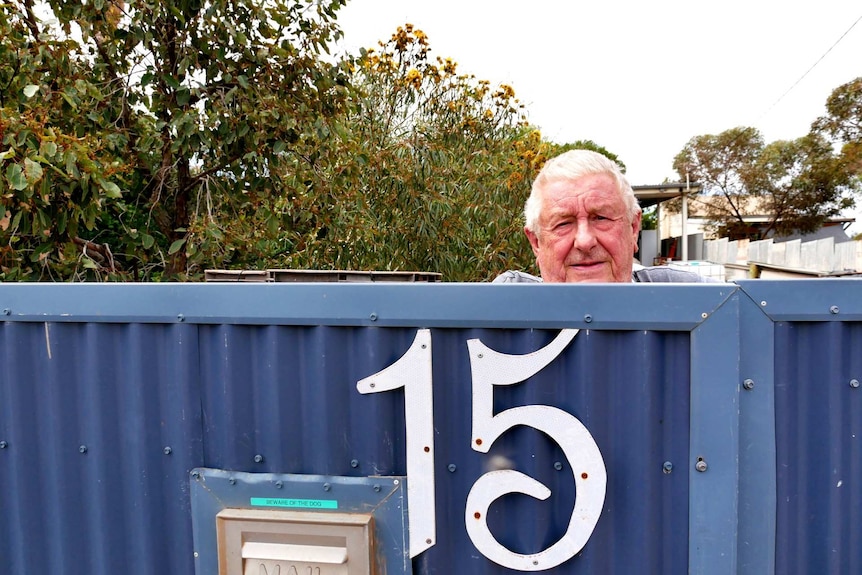 A man looking over his blue fence.