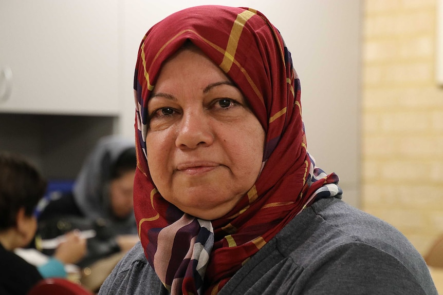 A headshot of a woman wearing a red headscarf and grey cardigan.