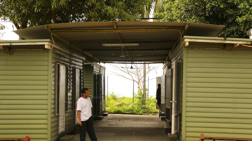 A man stands outside a demountable building on Manus Island.