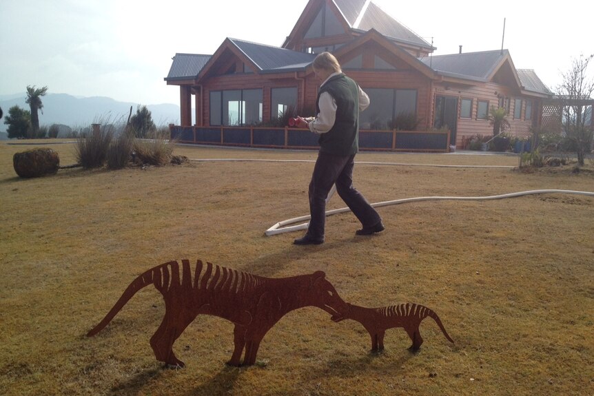 Tarkine Wilderness Lodge manager Maree Jenkins holds fire hose outside building.