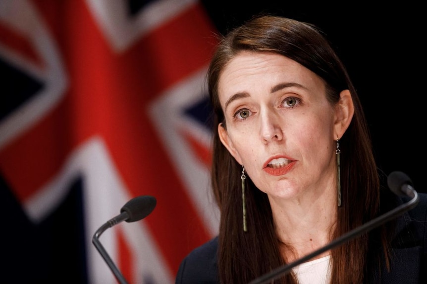 Jacinda Ardern addressing the public, with flag behind