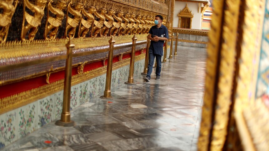 A man wearing a protective face mask visits a Thai temple.