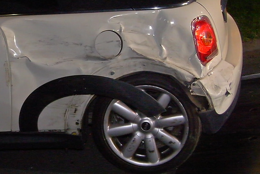 A white mini cooper has dents and scratches from being hit by another car.