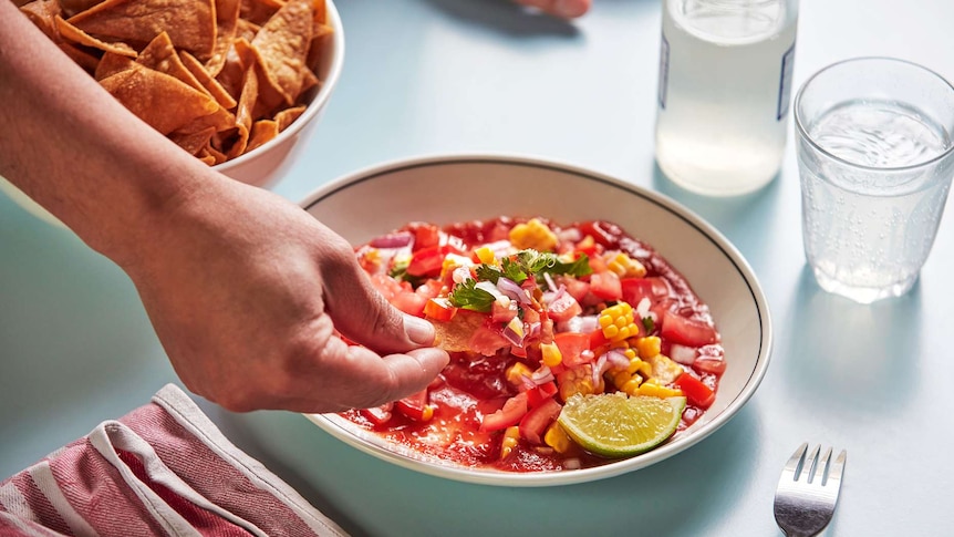 Salad salsa with tomatoes, corn and chips on a corn chip