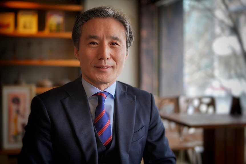 A Korean man in a suit with a slight smile on his face 