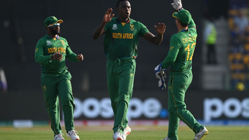 Two men of African descent celebrate a wicket with Quinton De Kock