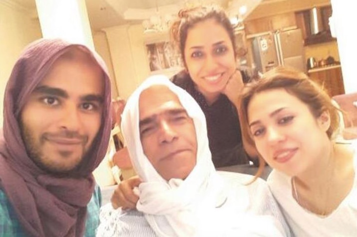 Two women pose with their father and cousin, who are wearing hijabs.