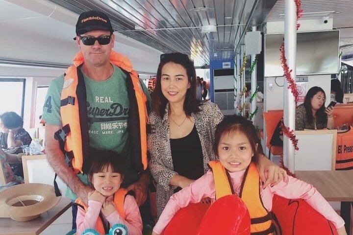 A husband and wife with their two daughters, who are wearing life jackets on a ferry.