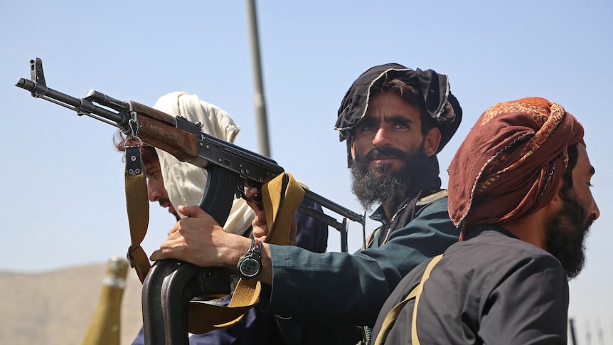 Un terroriste taliban se tient dans un véhicule à toit ouvert tenant une arme à feu à Kaboul.