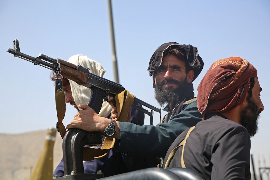 A Taliban terrorist stands in an open-top vehicle holding a gun in Kabul.