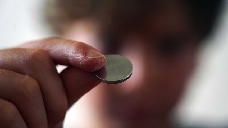 A close up view of a lithium button battery held by a seven-year-old boy.