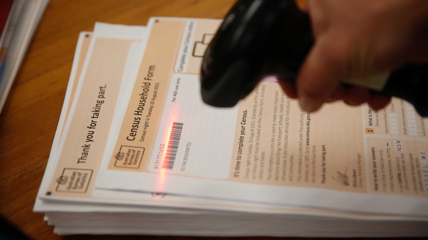 A barcode scanner is lighting up as it scans a barcode on a Census form. The form is white and beige.