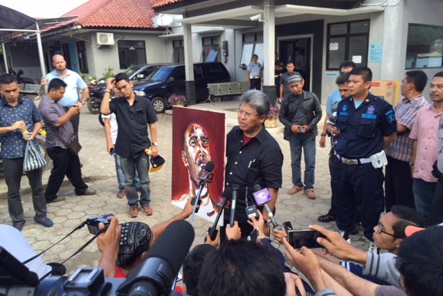 Lawyer Todung Mulya Lubis hold self-portrait by Myuran Sukumaran