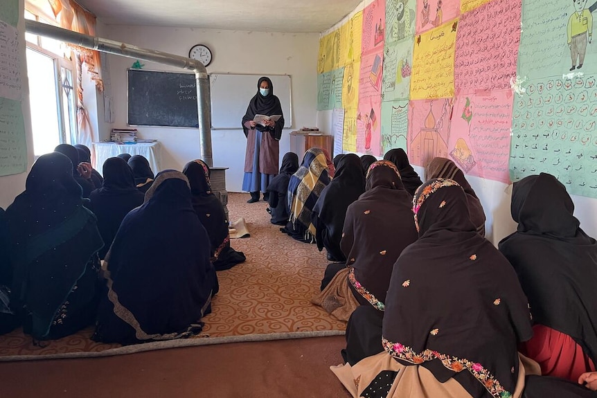 Girls sitting in a classroom with colourful posters on the wall. 