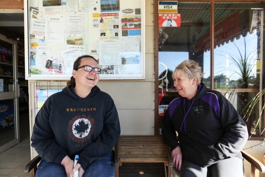 Two women share a laugh outside a corner store in an Australian country town