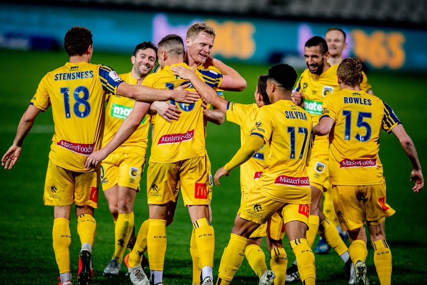 A group of A-League teammates run back to halfway after a goal.