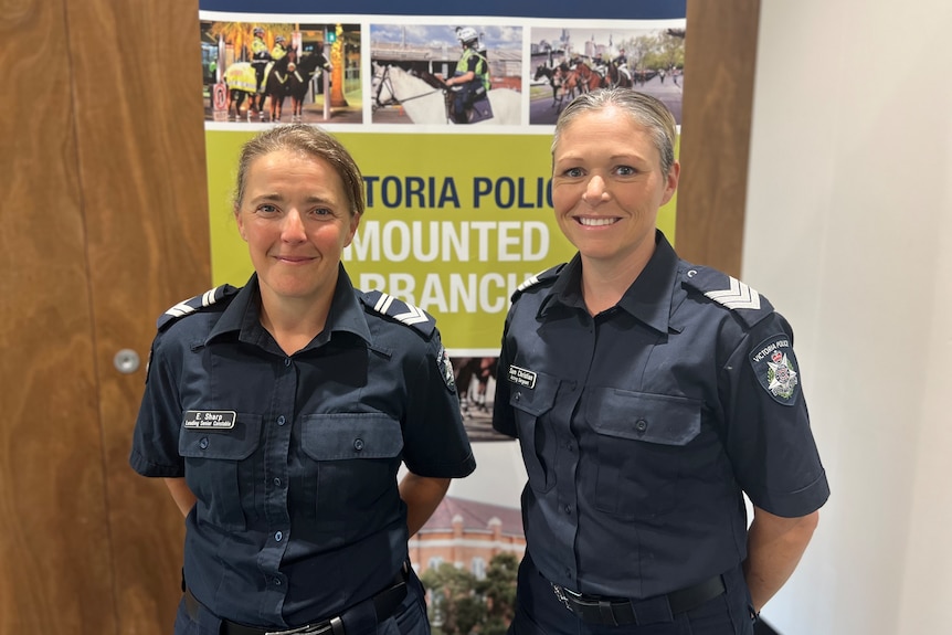 Two female police officers smile at the camera.