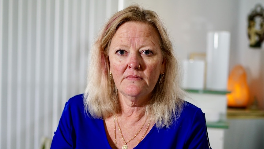 A woman looks into the camera with a serious expression on her face.