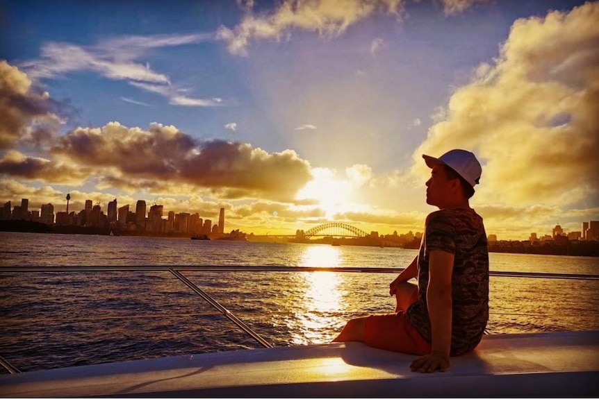 a man look the left at sunset with Sydney Harbor Bridge in the background