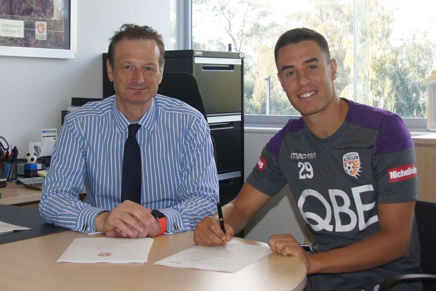 Chris Ikonomidis poses for a photo signing a contract to play with Perth Glory with Tony Pignata alongside him in an office.