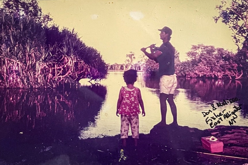 Sepia aged photo of dad and child fishing on a river bank.