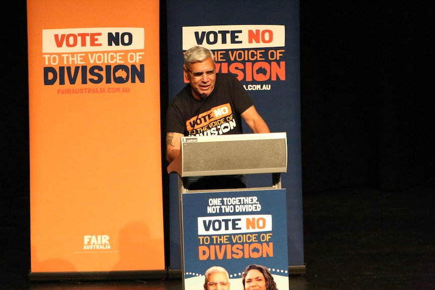 A man speaks at a lectern.