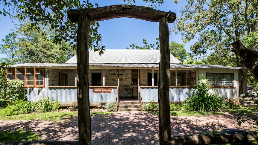 An aging wooden building with a tin exterior sits in bush land.