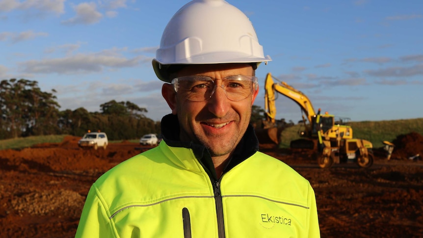 Man in hard hat stands in front of construction site