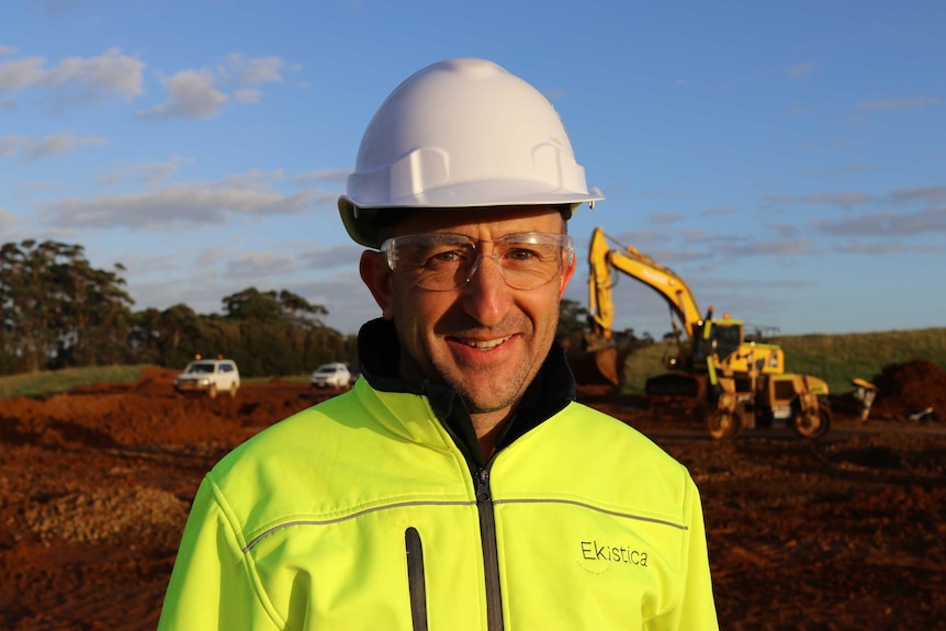 Man in hard hat stands in front of construction site