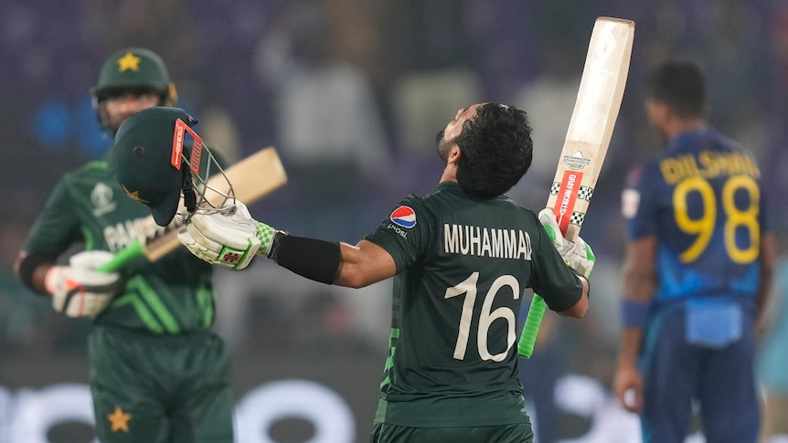 Mohammad Rizwan raises his bat and helmet during a Cricket World Cup match.