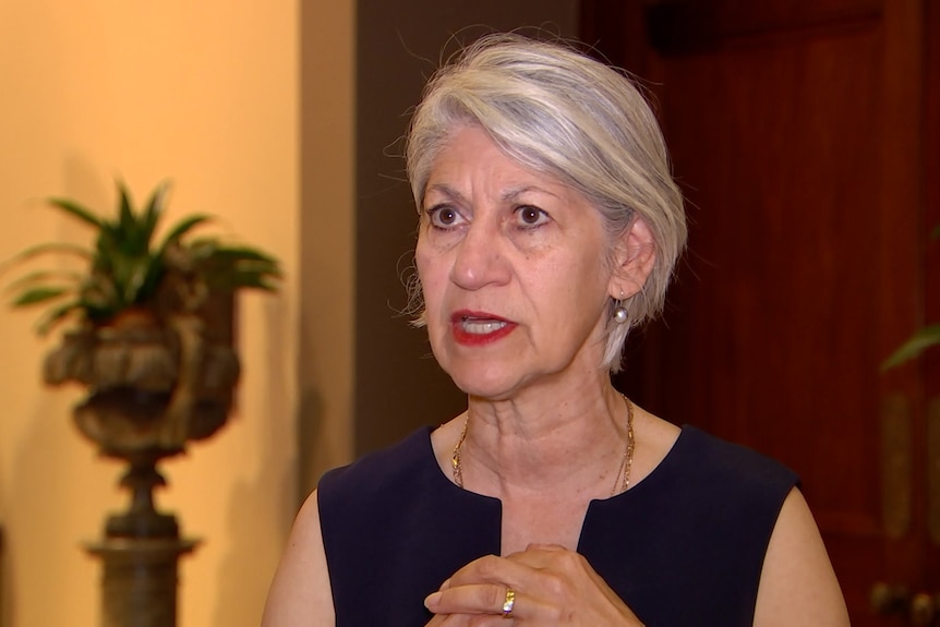 A woman with grey hair in a yellow and brown room