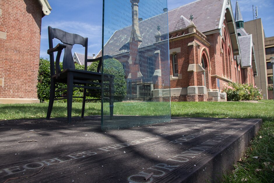 A chair in front of a glass pane with a plaque on the ground saying people's convention