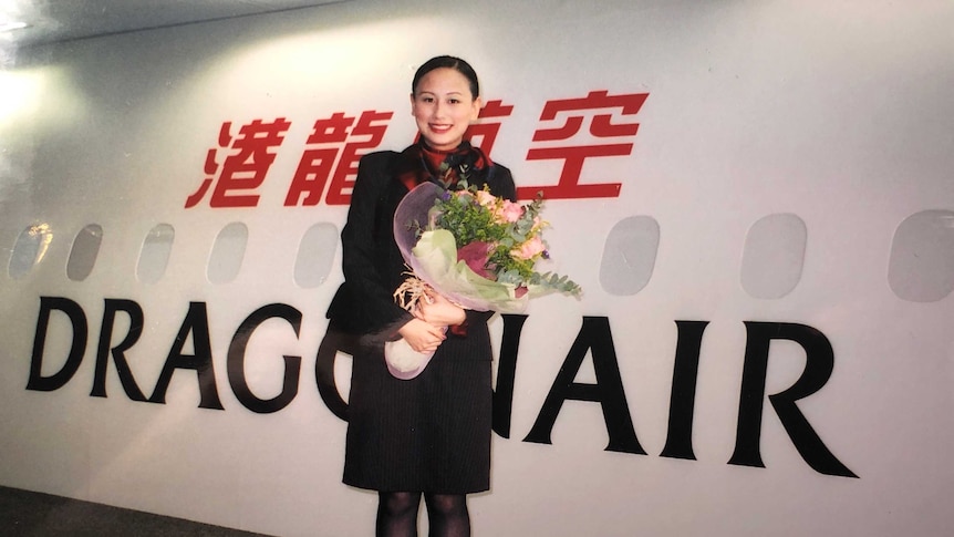 Rebecca Sy stands in front of a Dragonair plane, holding a bunch of flowers.