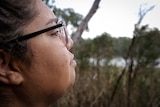 Side shot of young woman in glasses with meditative expression looking out at a wetland.