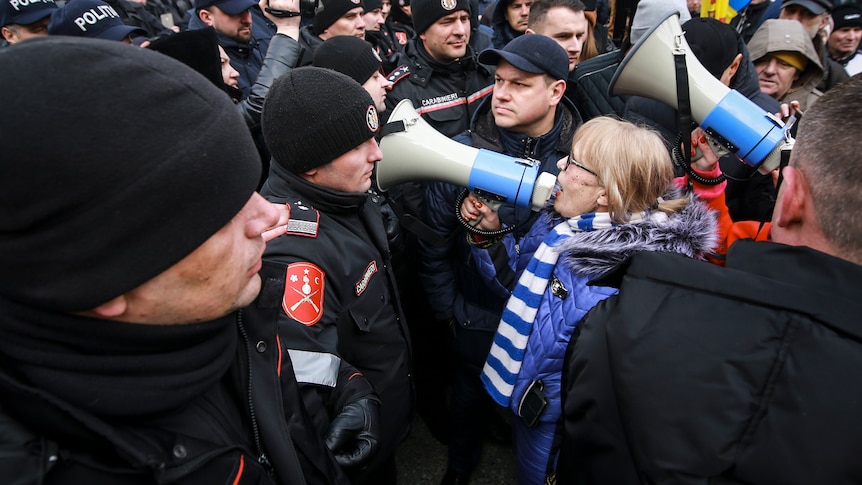 A woman yells through a bullhorn at police during a protest.