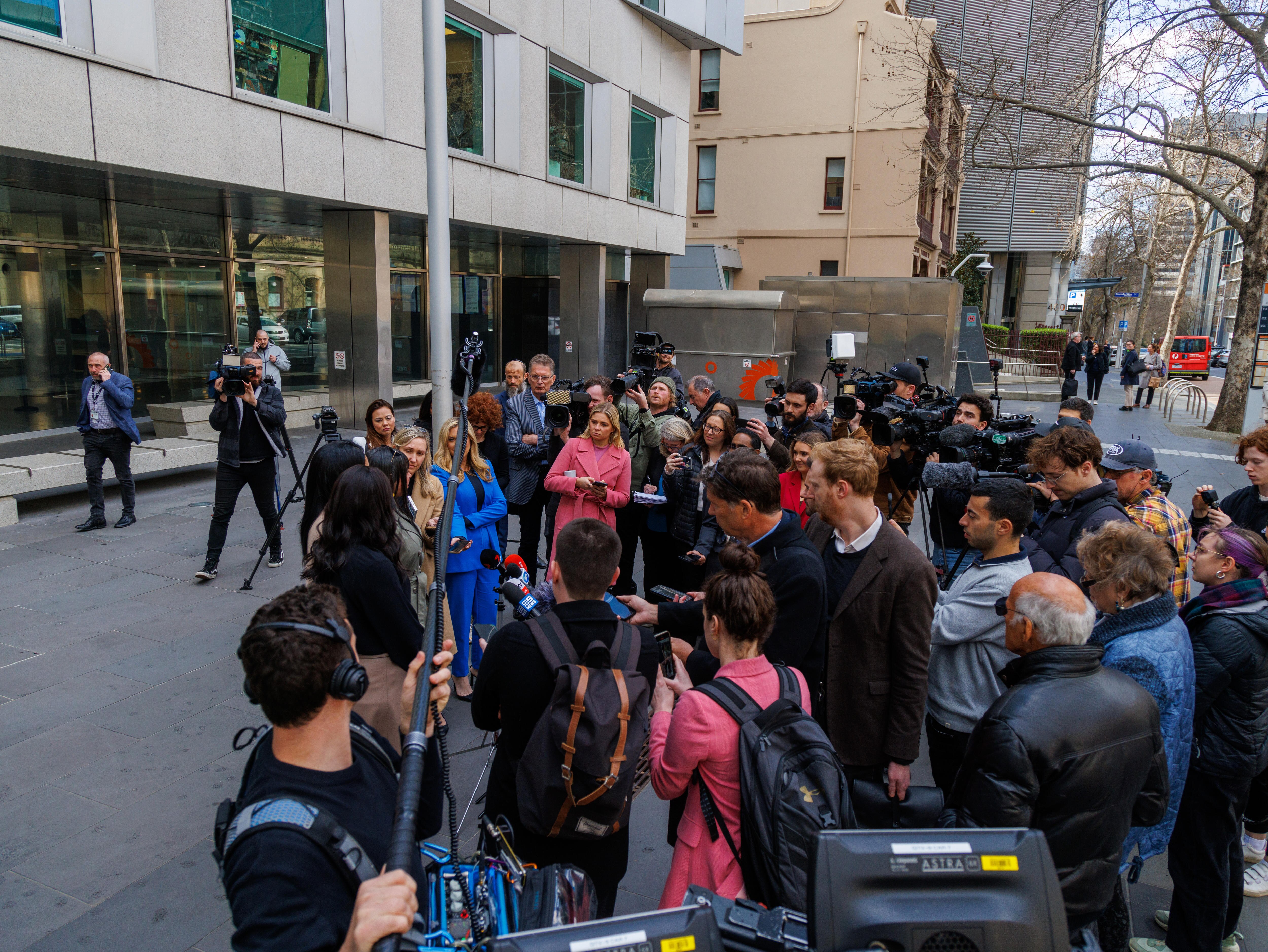 Reporters and camera operators surrounding three sisters