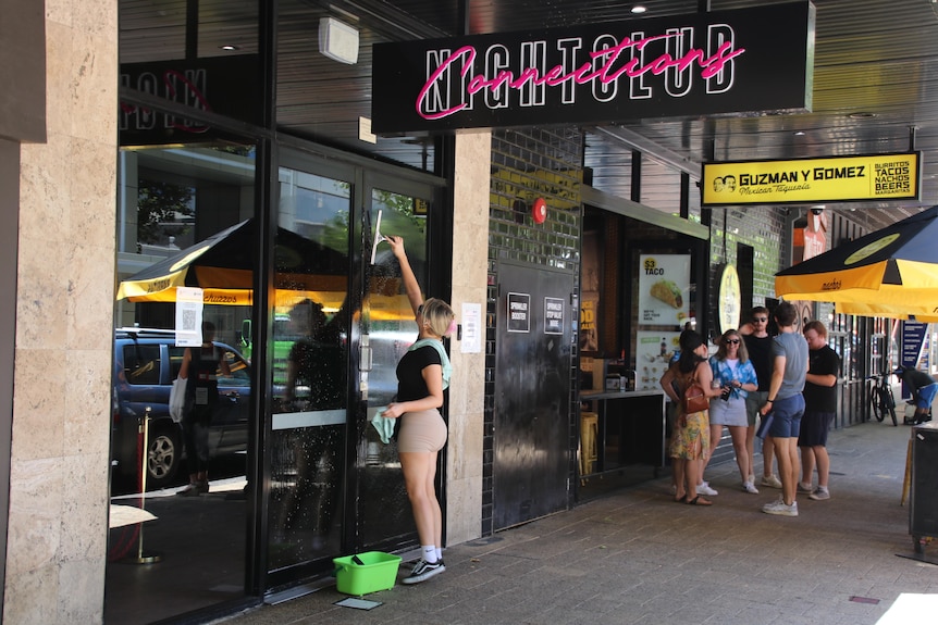 A woman washes the front windows of Connections Nightclub.