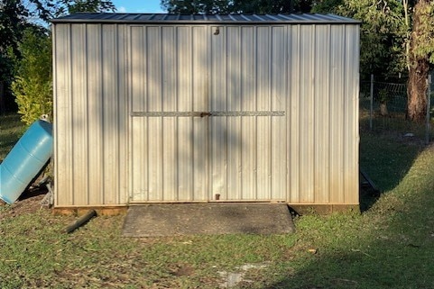 A garden shed with its doors closed in a grassy yard.