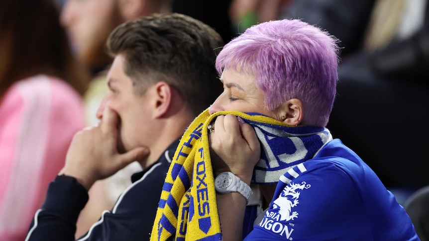 A leicester fan covers her face with her scarf