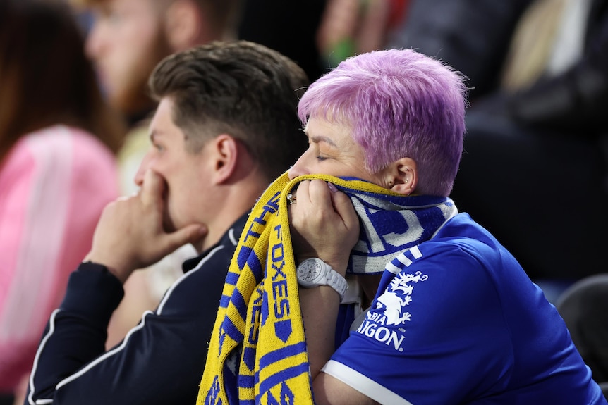 A leicester fan covers her face with her scarf