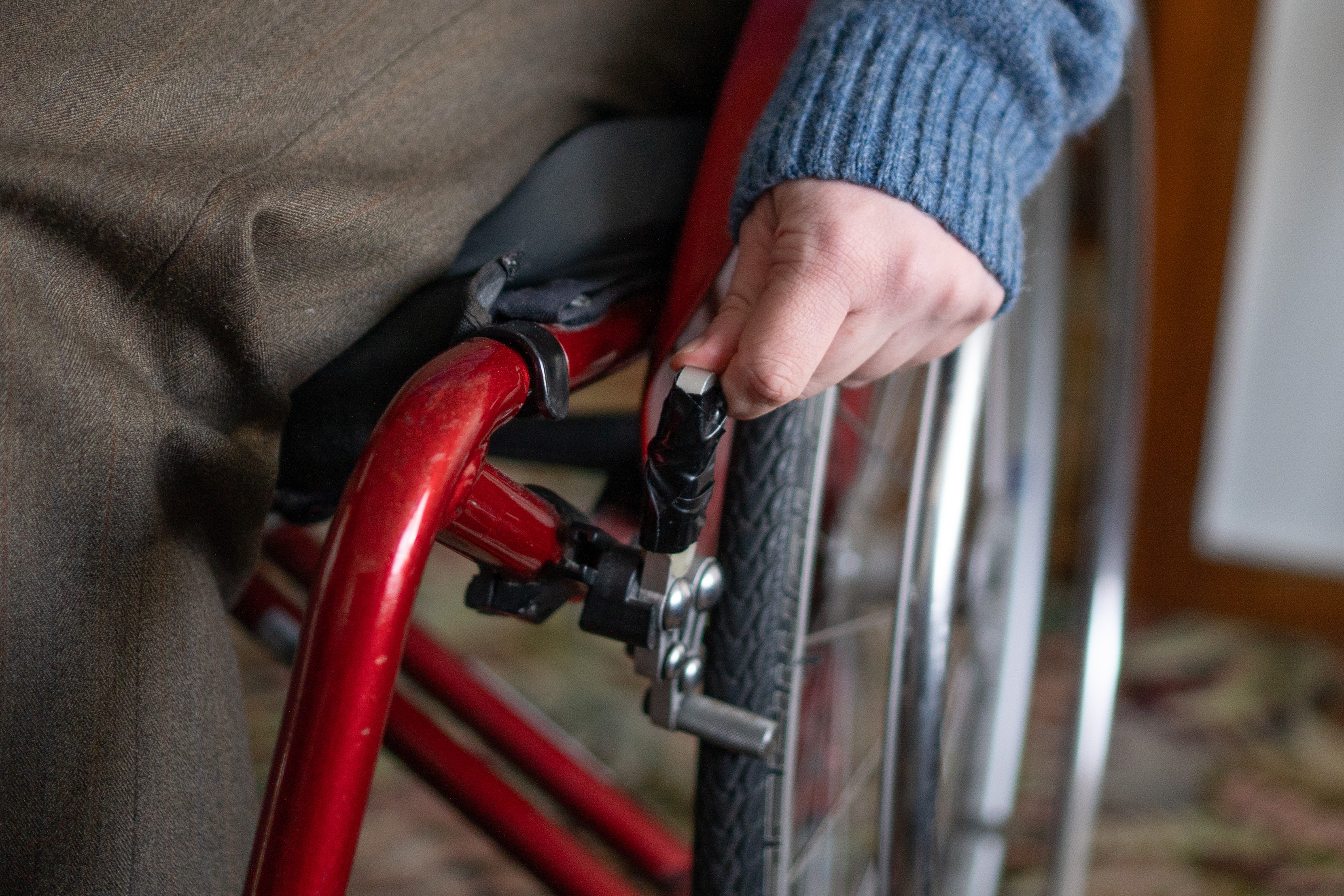 A hand touching duct tape on a wheelchair lever.
