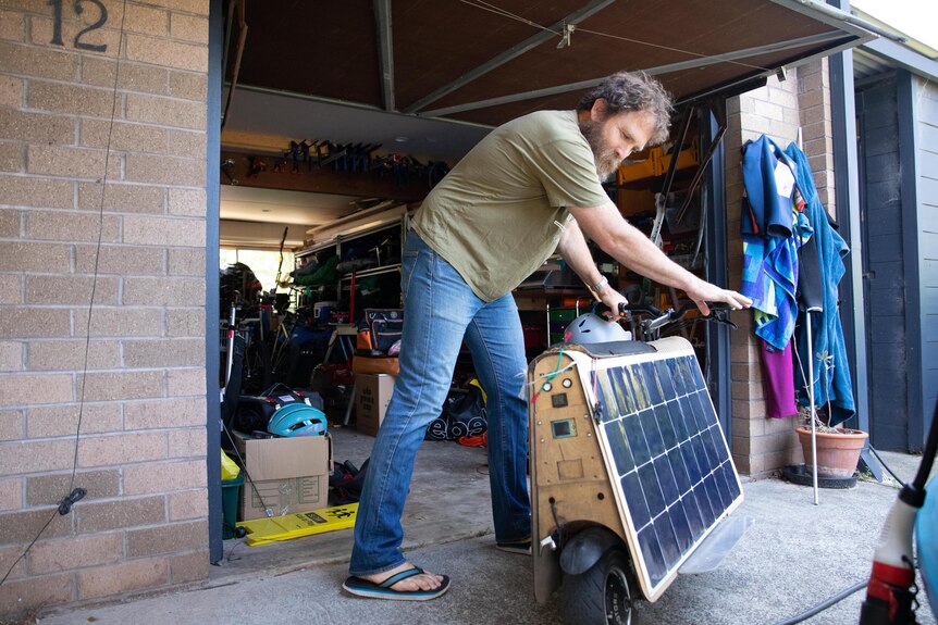 A man in T-shirt and jeans wheels out a solar panel invention.