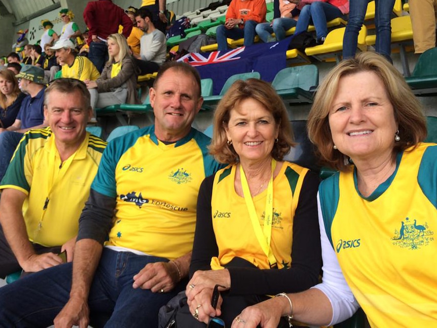 Barry Dwyer, Geoff Gohdes, Lea Dwyer and Kim Gohdes sit next to each other in a grandstand wearing gold and green colours