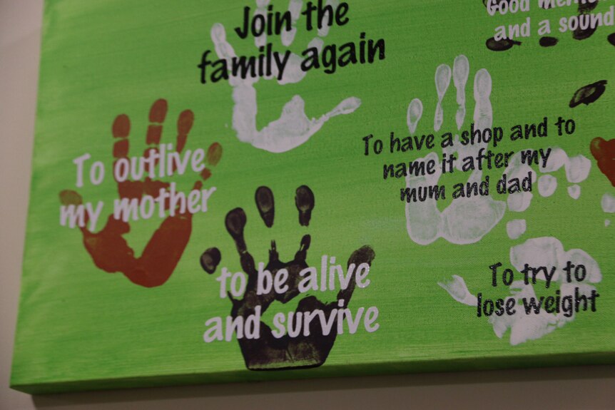 A mural of handprints with positive messages written on it.