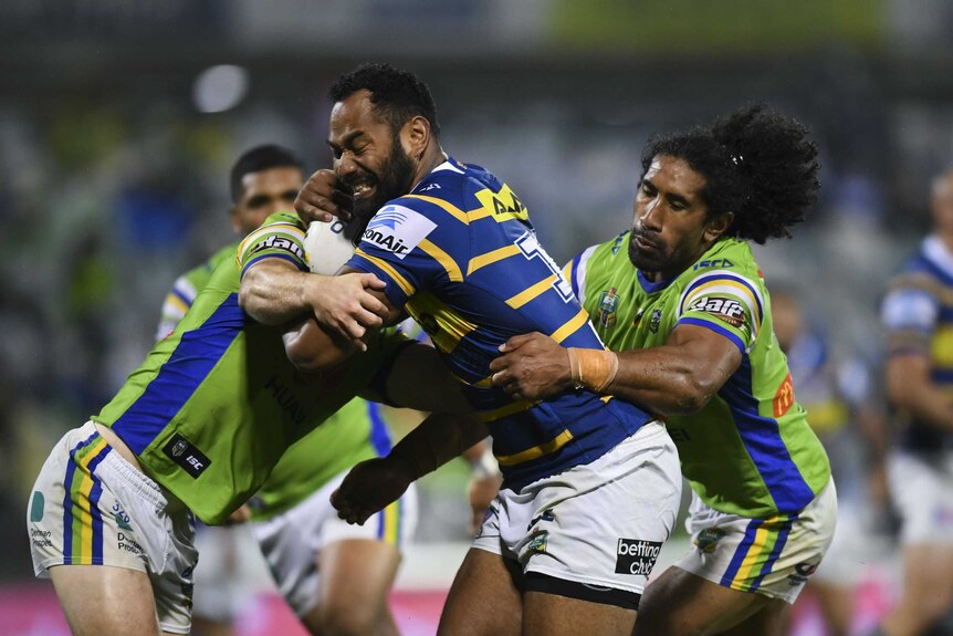 Parramatta player Tony Williams is tackled by Canberra Raiders
