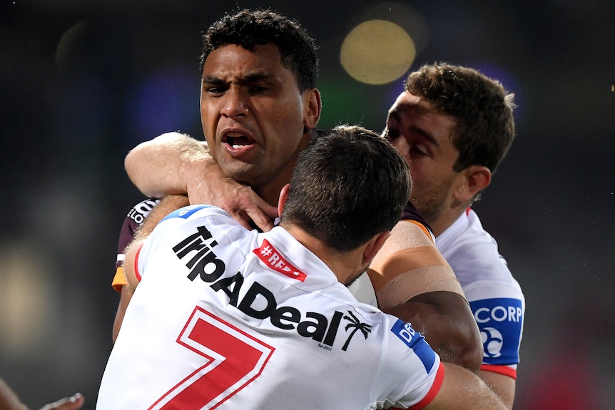 A Brisbane Broncos NRL player stands in a tackle against the St George Illawarra Dragons.