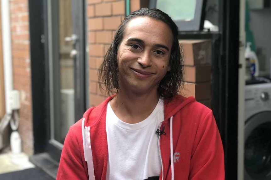 Davey Thomson smiles for a photograph taken outside a house.