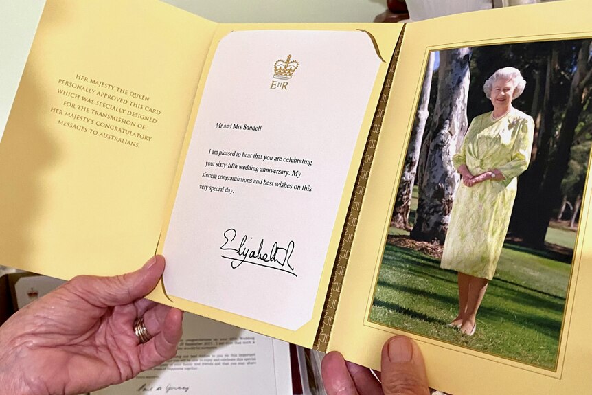Woman holds a card from The Queen