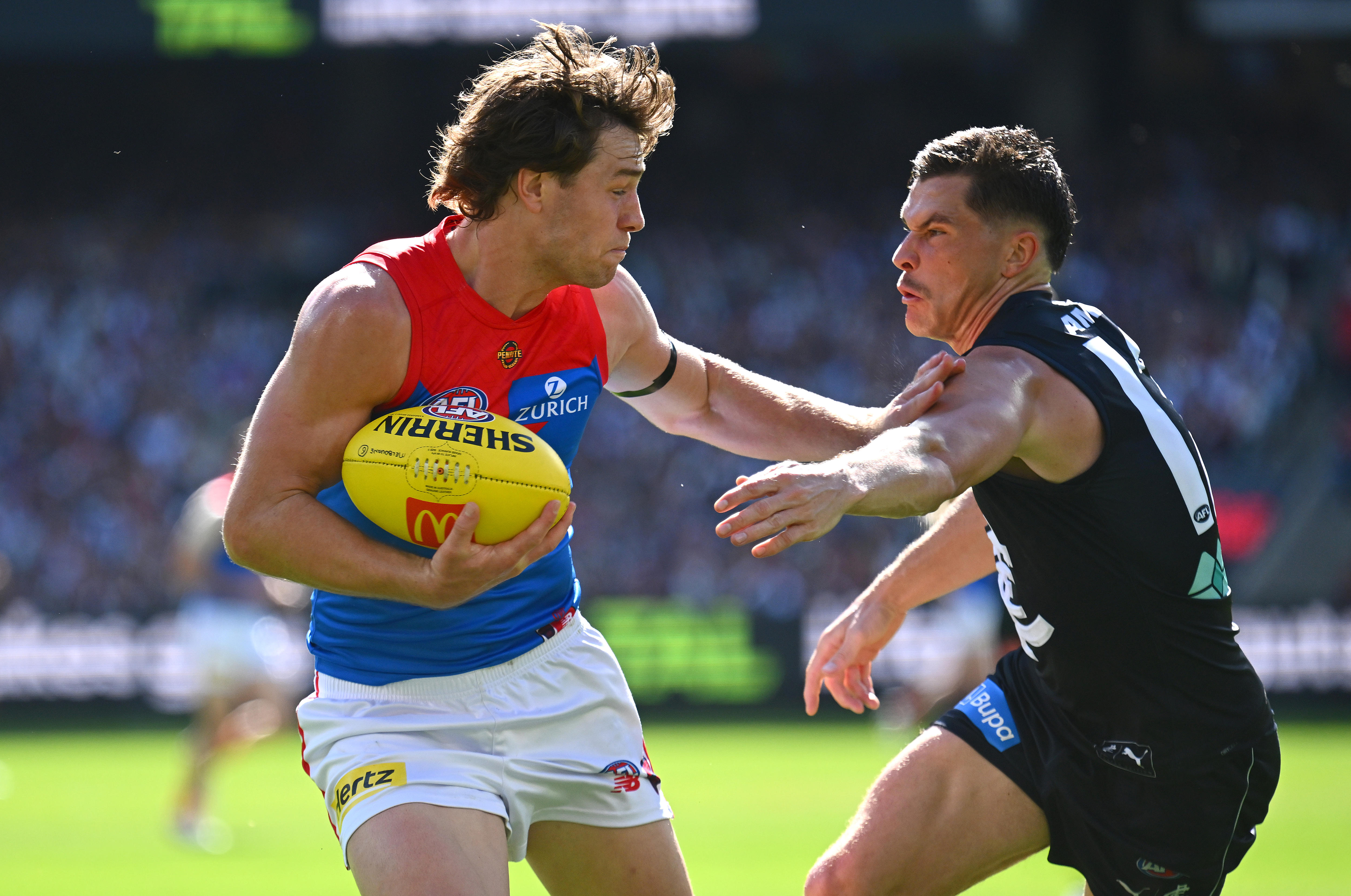 Tom Sparrow of the Demons fends off a tackle by Ben Ainsworth of the Blues during a 2026 AFL match.
