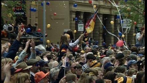 A crowd of football supporters in the street in celebration with flags and balloons